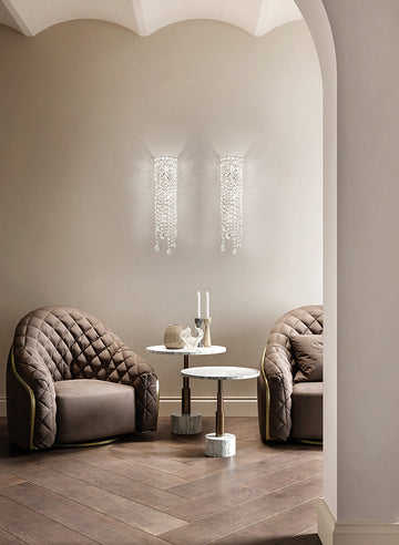 Modern interior with two upholstered chairs and a small table against a neutral wall.