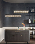 Modern kitchen with dark island and hanging crystal chandeliers from Masiero against a dark wall.