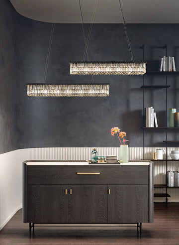 Modern kitchen with dark island and hanging crystal chandeliers from Masiero against a dark wall.