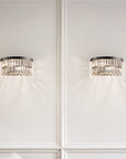 Two crystal wall sconces on a white paneled wall with a modern interior setting.