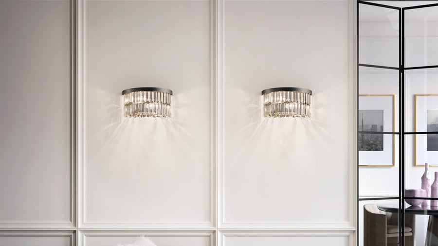 Two crystal wall sconces on a white paneled wall with a modern interior setting.