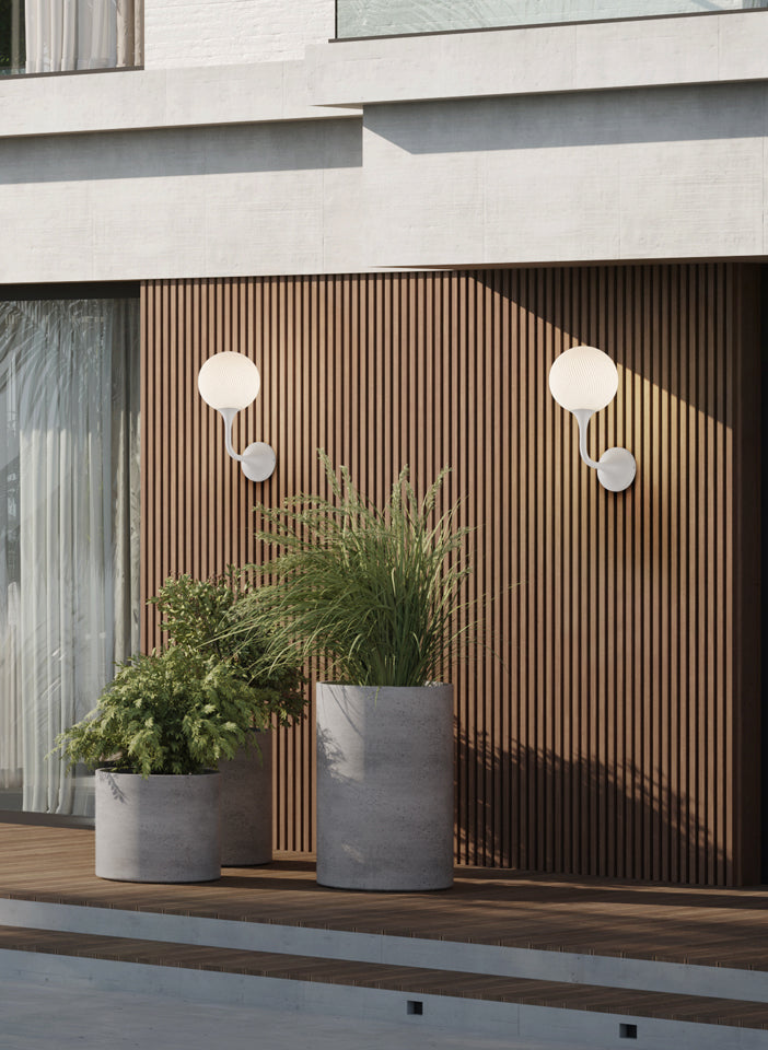 Modern outdoor setting with wall lights and potted plants in front of a building.