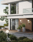 Modern house exterior with large windows, plants, and a view of the ocean and outdoor wall lights by Masiero