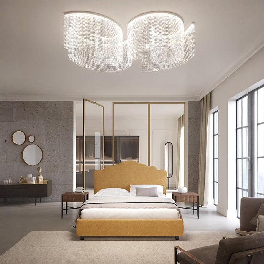 A grand ceiling crystal chandelier from Masiero available at Spacio, in a modern bedroom setting