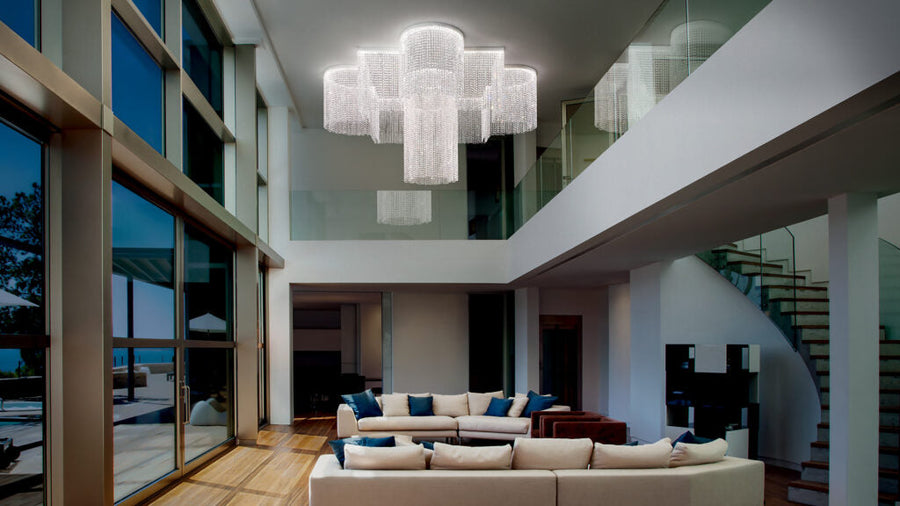 Modern living room with a chandelier, sofa, and staircase.
