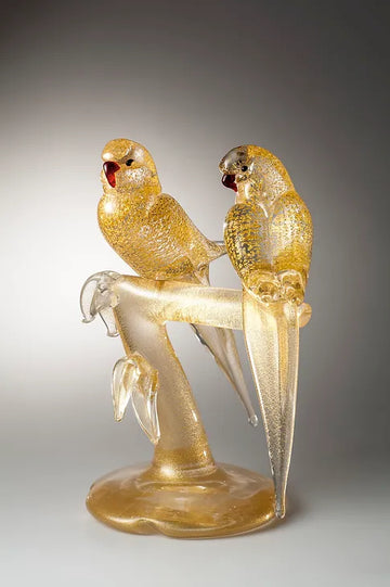A pair of Murano 2 Gold Parakeets sitting on a branch, perfect for home decor.