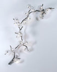 Decorative wall light fixture shaped like a branch with lights on a white background