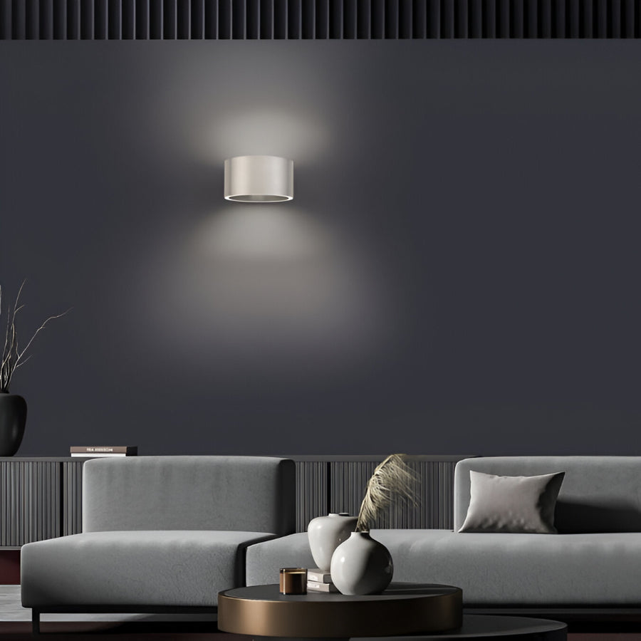 Modern living room with a gray sofa, decorative vases, and a wall-mounted rechargeable light fixture.
