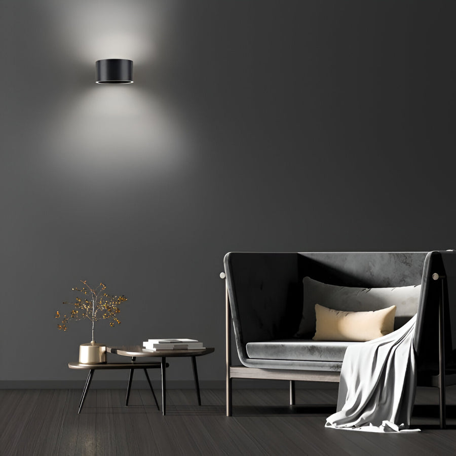 Modern living room with a gray sofa, coffee table, and wall lamp against a dark gray wall.