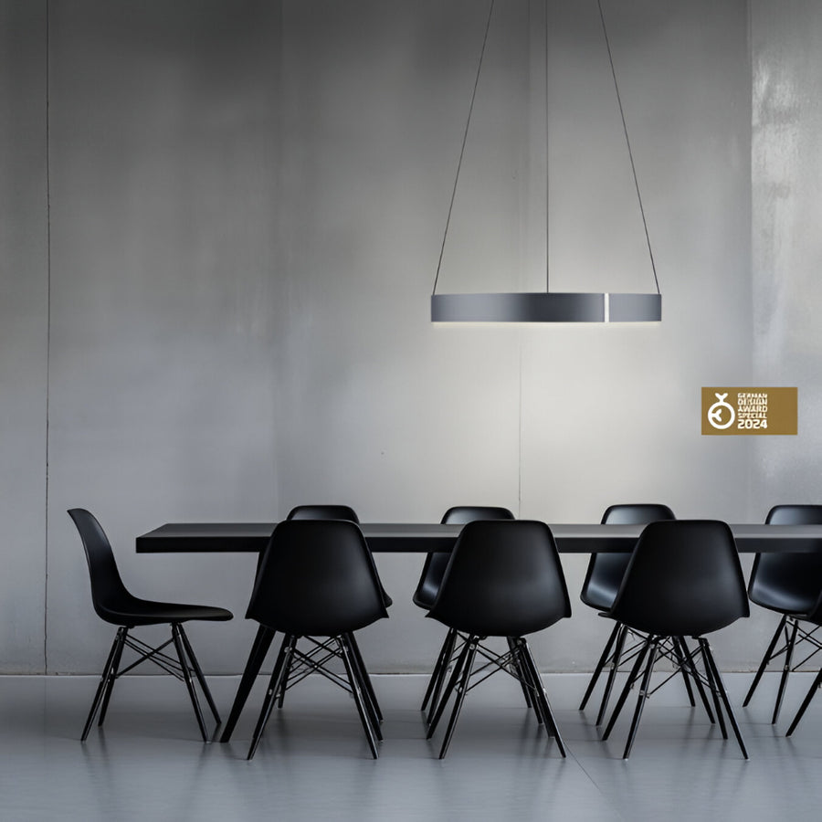 Modern black dining table with chairs under a pendant light in a minimalistic setting.