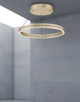 Gold circular pendant light hanging in a room with gray walls.