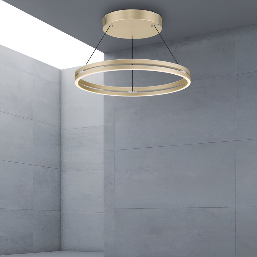 Gold circular pendant light hanging in a room with gray walls.