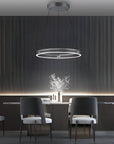 Modern dining room with a kinetic chandelier, table, and chairs against a dark wall.