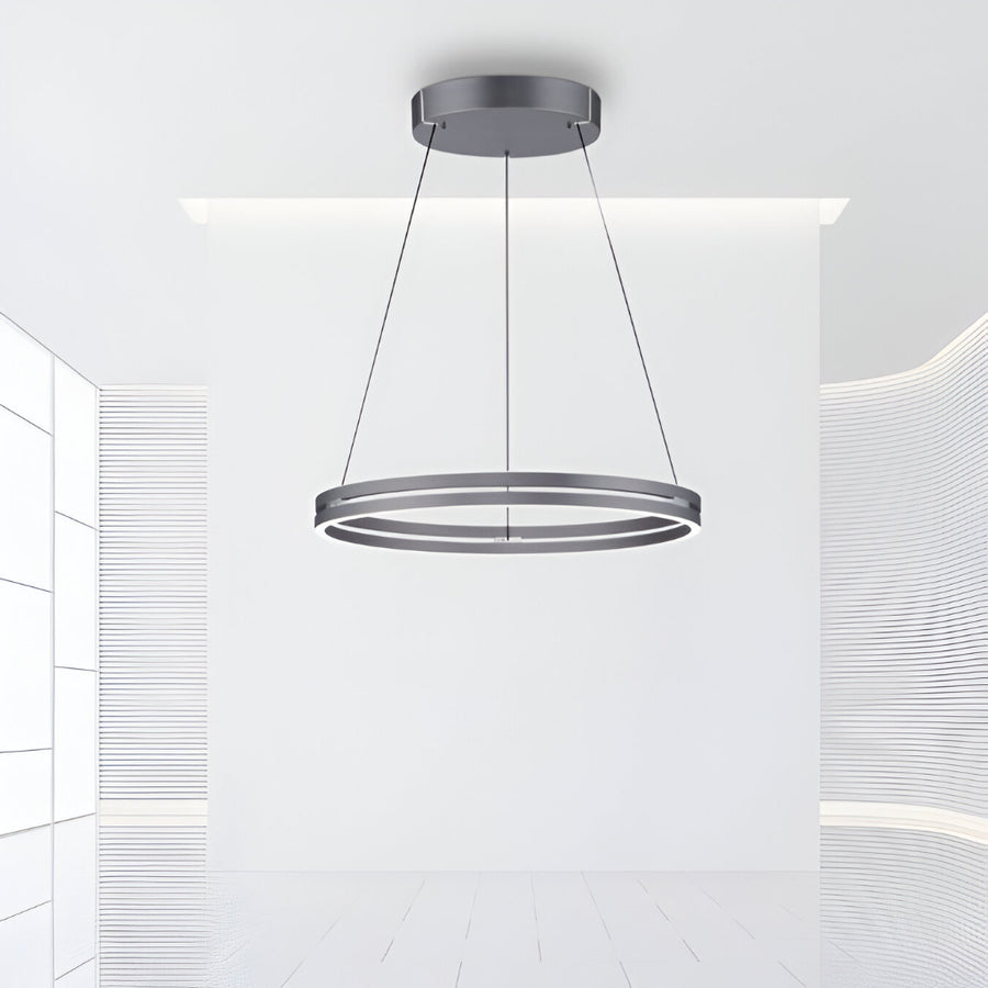 Modern pendant kinetic light fixture hanging from the ceiling in a minimalistic room.