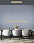 Modern dining room with a long table and chairs, featuring suspension pendant kinetic lights against a gray wall from Neuhaus Pure, available at Spacio retail store in Mumbai & Kolkata. 