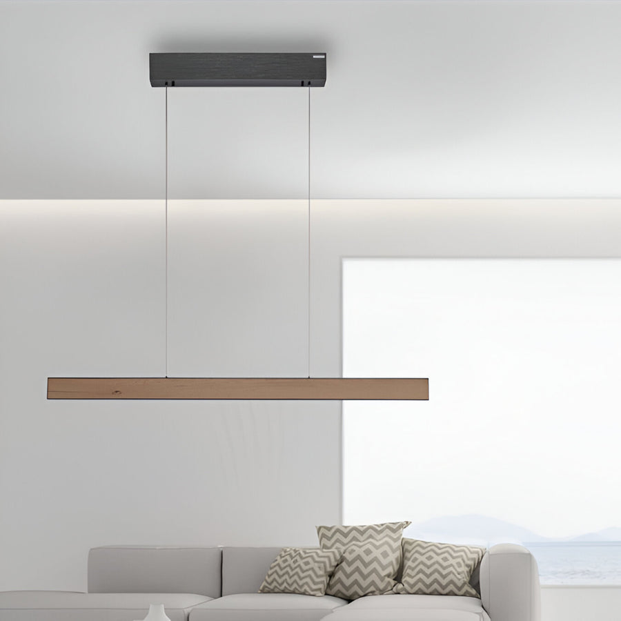 Modern pendant light fixture hanging above a sofa with decorative pillows in a minimalistic living room.