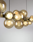 Gold spherical pendant kinetic light fixture on a plain background