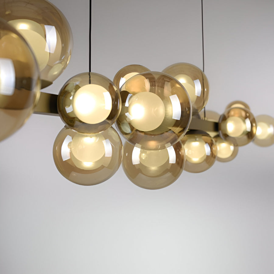 Gold spherical pendant kinetic light fixture on a plain background
