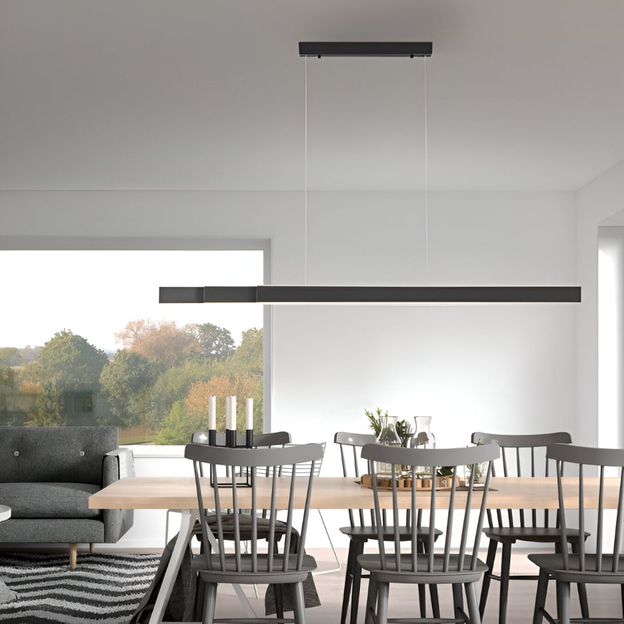Modern dining room with a long wooden table and chairs, featuring a black pendant Kinetic light.