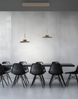 Modern black chairs around a dining table with pendant lights in a minimalistic setting.
