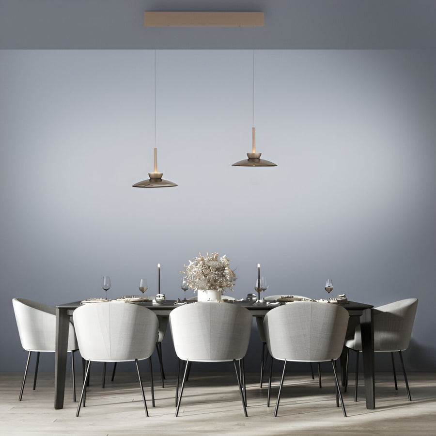 Dining room with a long table and chairs against a gray wall.