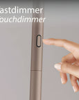 Hand pressing a touch dimmer switch on a light fixture with text 'Tastdimmer Touchdimmer'.
