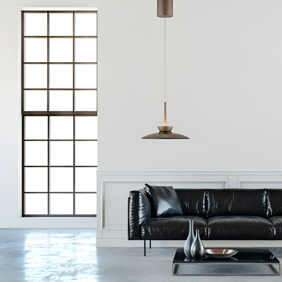 Modern living room with black leather sofa, decorative pillows, and a pendant light.