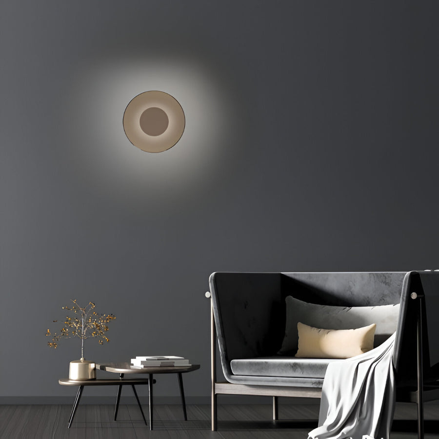 Modern wall light fixture on a dark gray wall with a sofa and side table in the foreground.