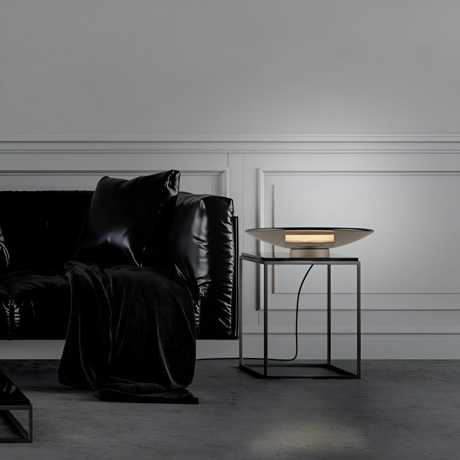 Modern living room with black leather sofa and side table against a gray wall with a Neuhaus Pure Moon table lamp, available at Spacio in India. 