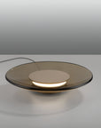 Modern glass table lamp with a smoked glass shade on a neutral background