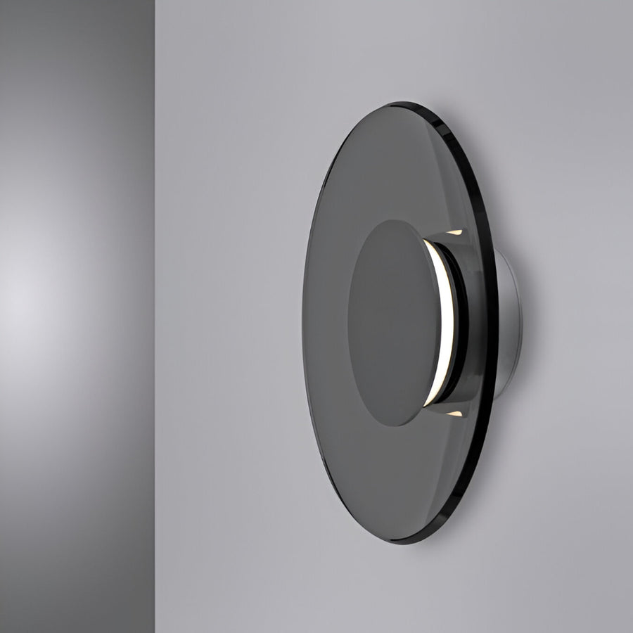 Round metallic wall light fixture on a gray background