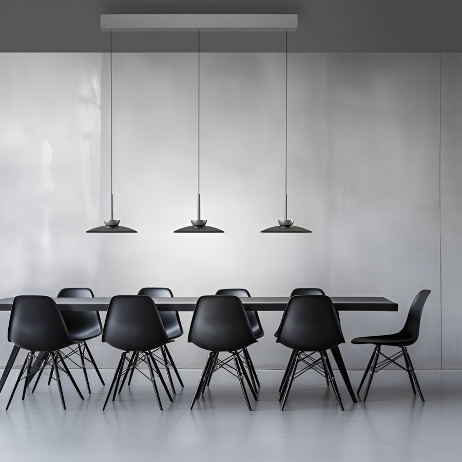 Modern black dining table with chairs and kinetic pendant lights in a minimalistic setting.