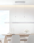 Modern dining room with a long rectangular table and chairs, featuring a pendant light fixture.