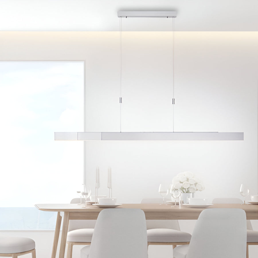 Modern dining room with a long rectangular table and chairs, featuring a pendant light fixture.