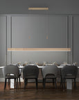 Modern dining room with a long table and chairs under kinetic pendant lights.