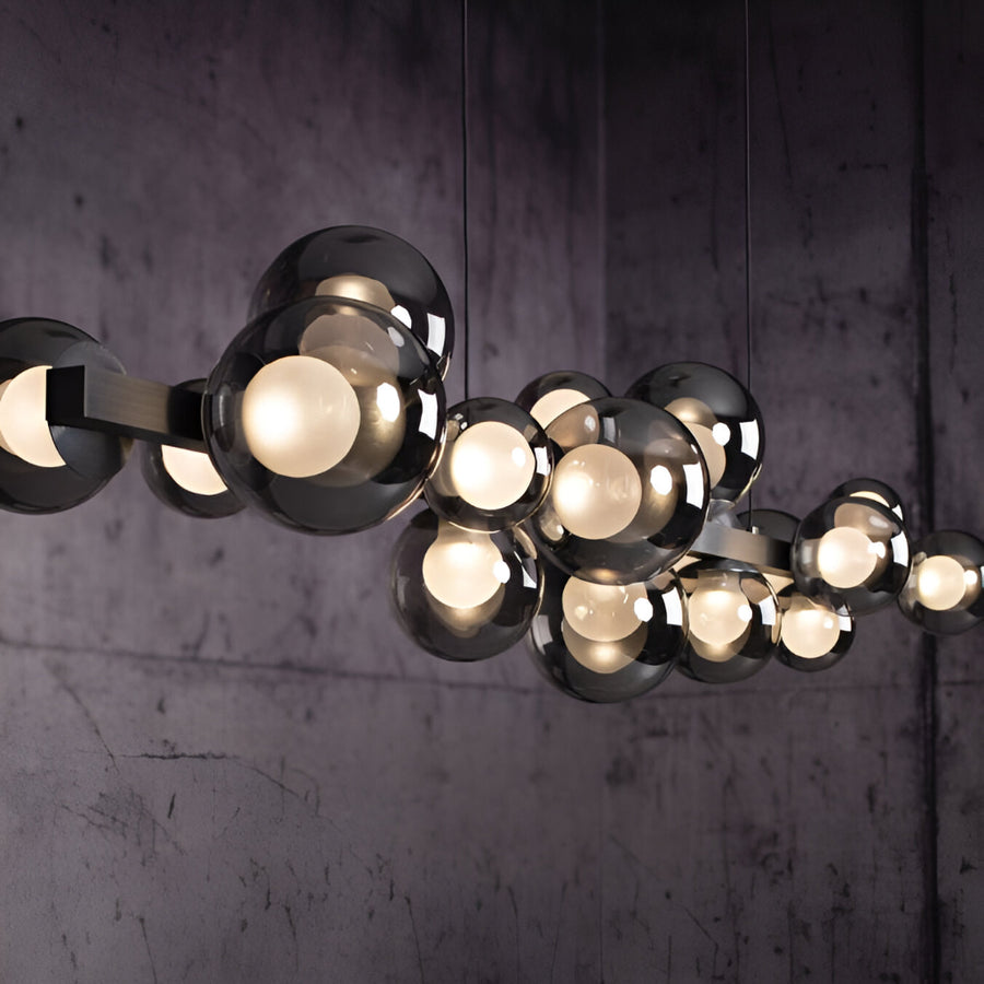 Modern kinetic chandelier with multiple light bulbs against a dark textured wall