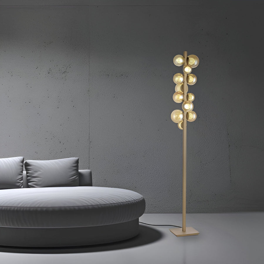 Modern floor lamp with multiple bulbs next to a gray sofa against a gray wall.