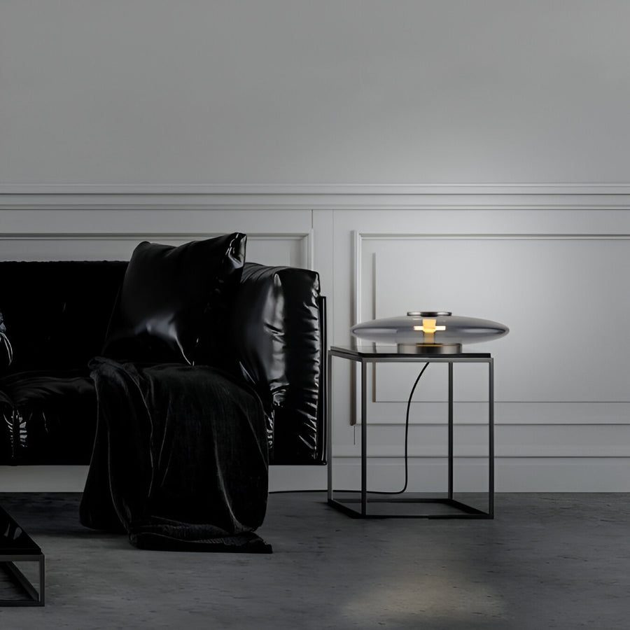 Modern living room with black leather sofa and side table against a gray wall.