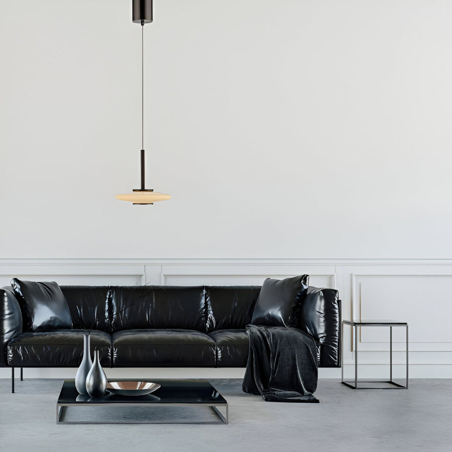 Modern living room with a black leather sofa, side table, and pendant light.