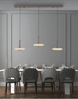 Dining area with gray chairs and a long table under pendant lights in a modern interior.