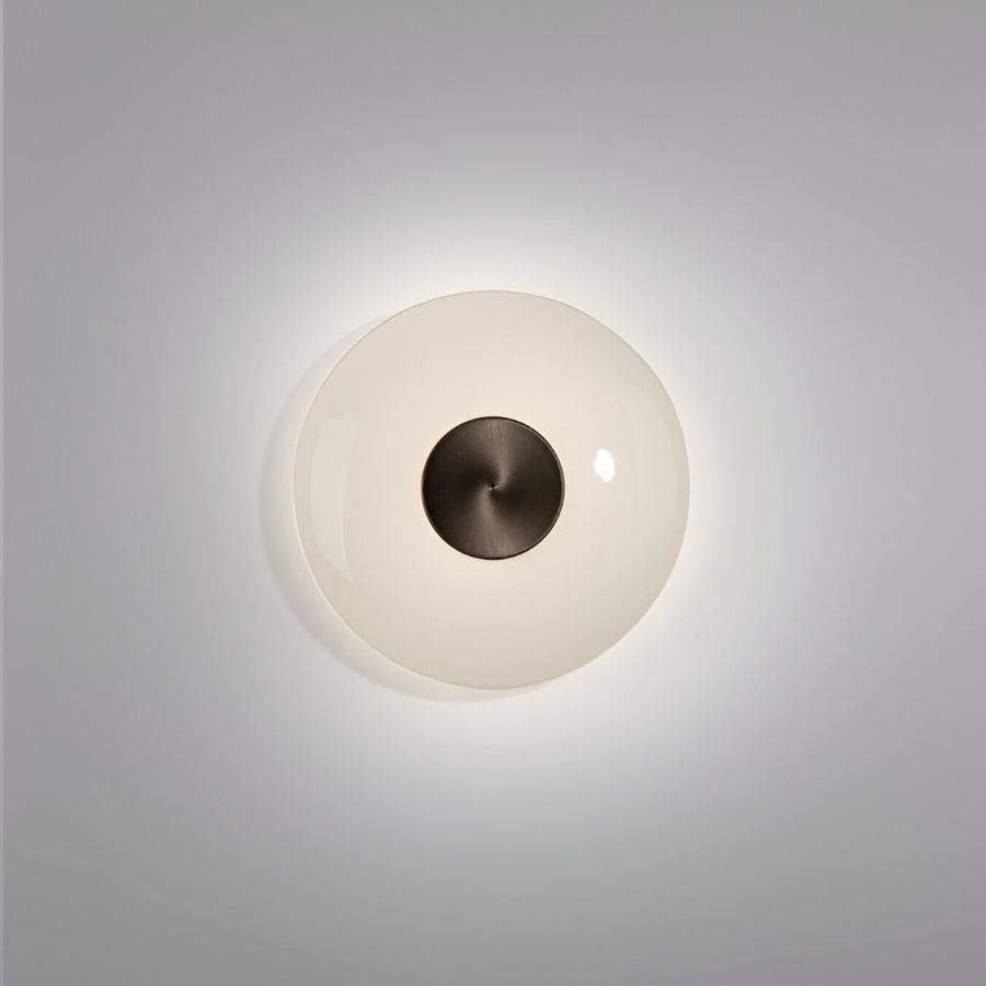 Round wall light fixture with a white glass cover and dark metal fixture on a gray background