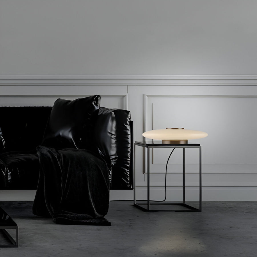 Modern living room with a black leather sofa and a side table with a lamp.