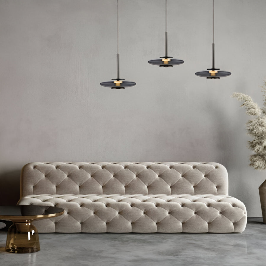 Beige tufted sofa in a modern living room with pendant lights and a neutral color palette.