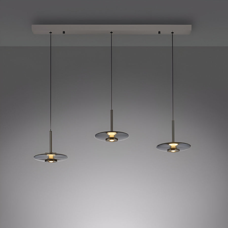 Three modern pendant lights hanging from a ceiling fixture against a gray background