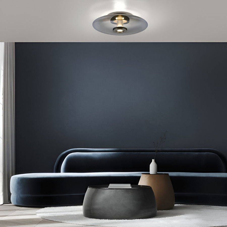 Modern living room with a dark gray sofa, round ottoman, and a dark wall.