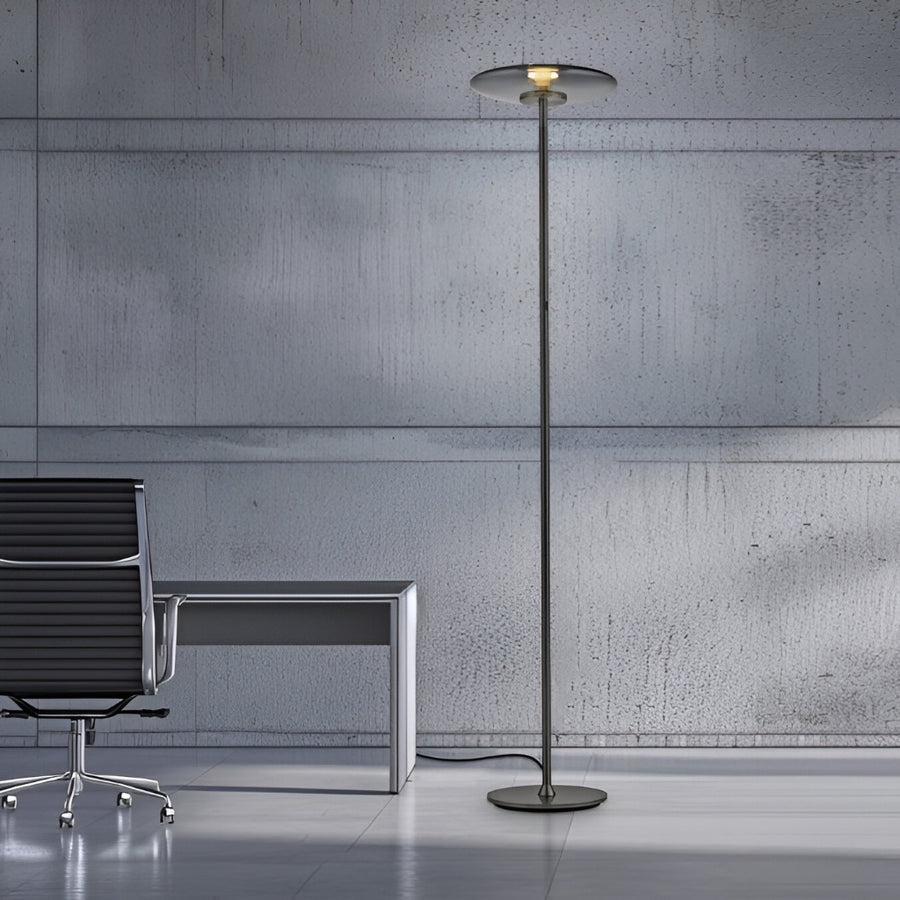 Modern floor lamp in a minimalistic office setting with concrete wall and chair.