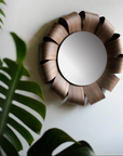 Decorative wall mirror with a unique wooden frame on a white wall.