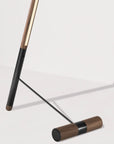 Close up of walnut wood and black floor lamp on a light gray background