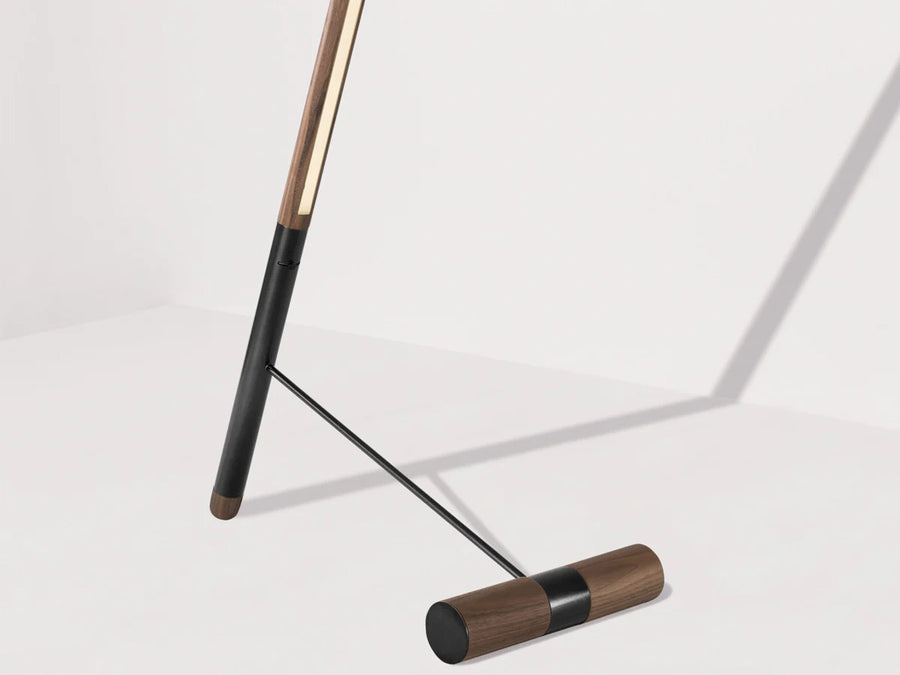 Close up of walnut wood and black floor lamp on a light gray background