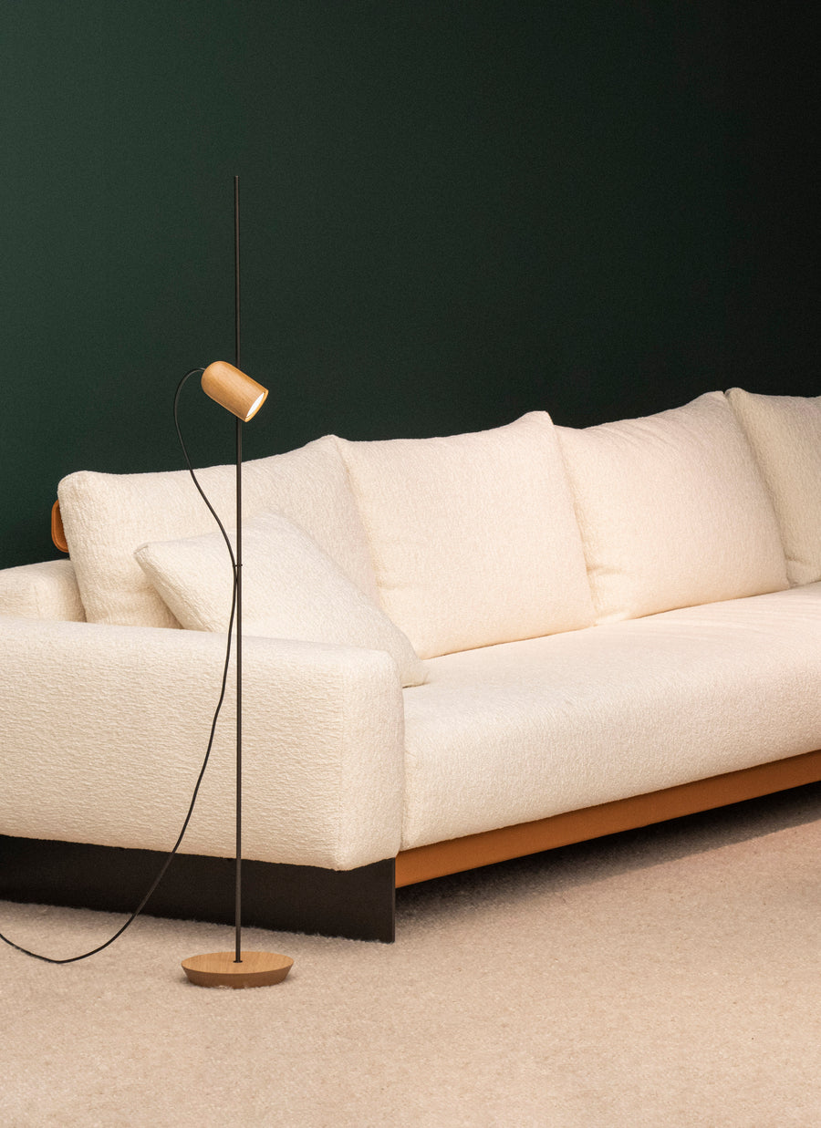 Beige sofa with a modern floor lamp against a dark wall